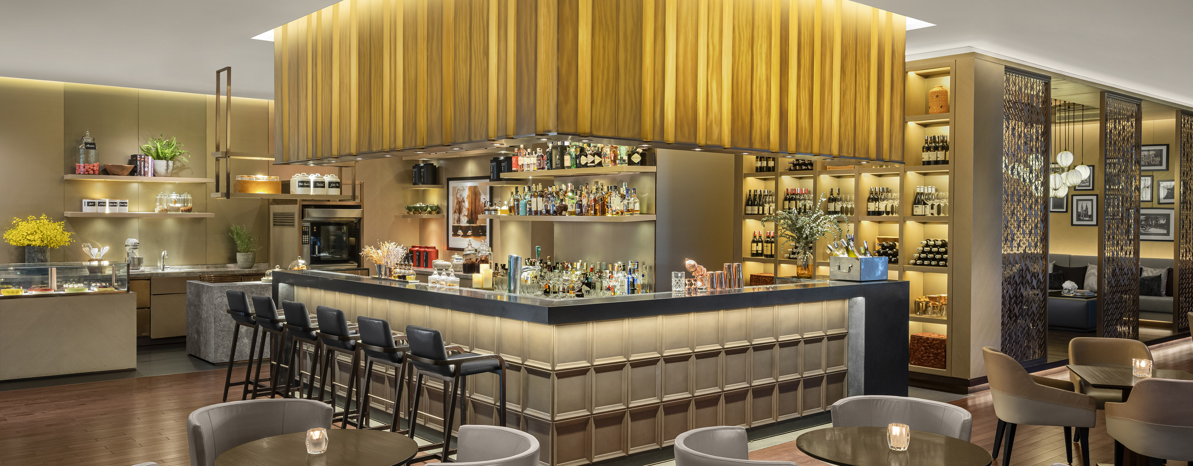 Interior of a restaurant bar and lounge in Ho Chi Minh City showing a bar area with stools and three shelves filled with various types of alcohol and liquor at New World Saigon hotel.